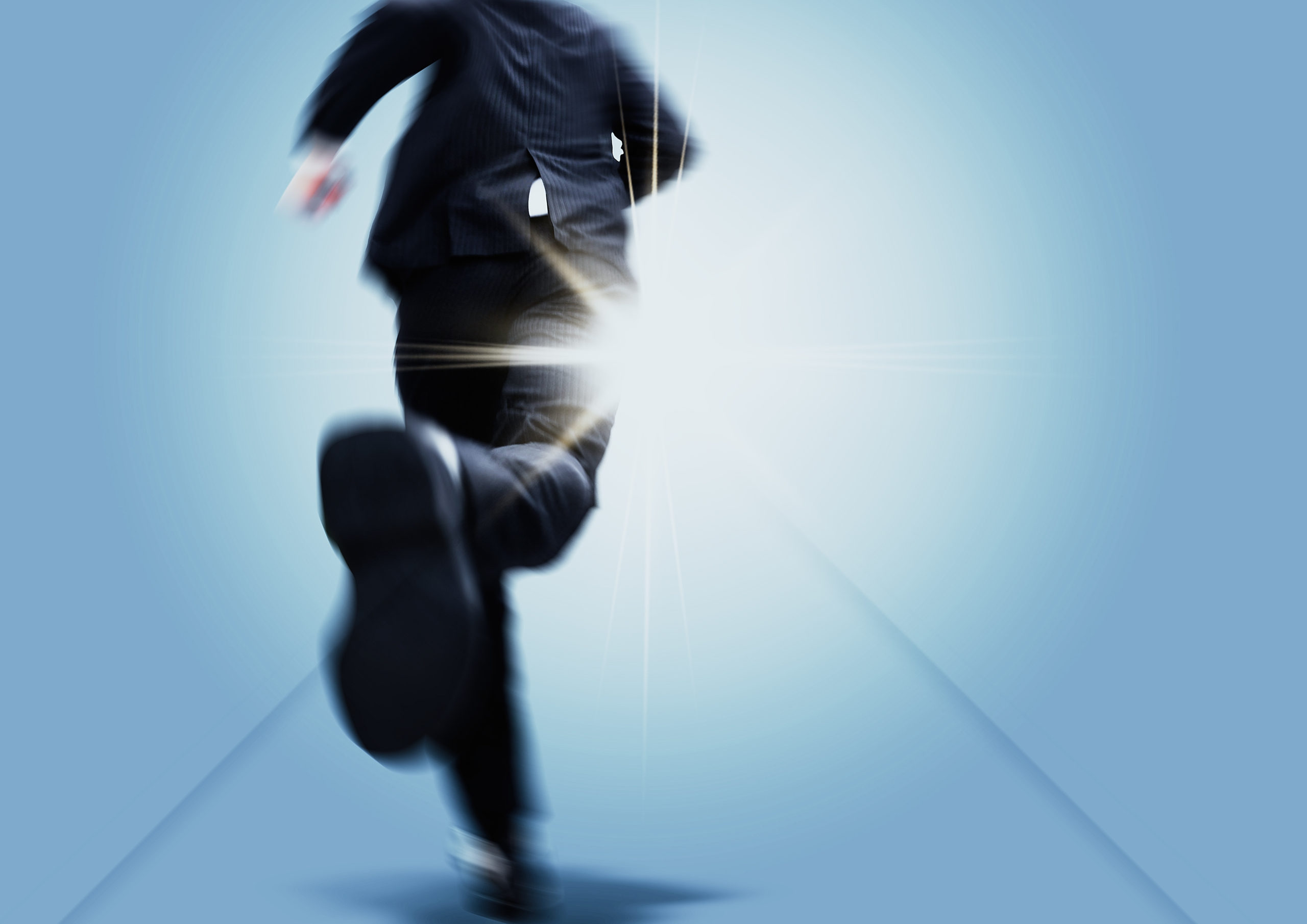 光の射す方向を目指して走るビジネスマン